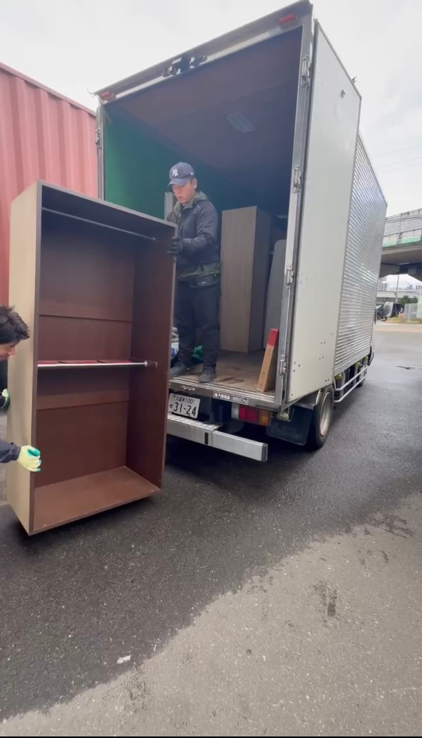 スタッフが丁寧に家具を運び出している後ろ姿の写真